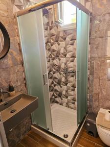 una ducha con una puerta de cristal junto a un lavabo en petros house, en Sarti