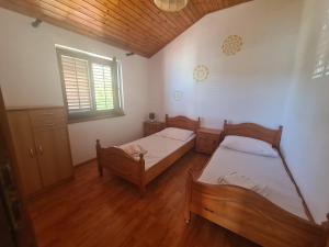 a bedroom with two beds and a window and wooden floors at Apartment Zaglav 2 - first sea row in Zaglav