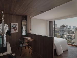 a hotel room with a bed and a desk and a window at Public House Hotel - Sukhumvit 31 in Bangkok