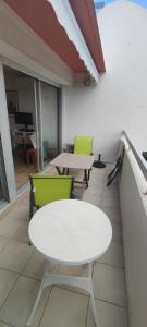 - Balcón con mesa blanca y sillas verdes en Joli studio avec piscine à 200m de la plage parking privé, en La Grande-Motte