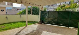 a large green gate on a patio with grass at Kaléstia in Kavála