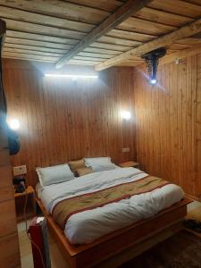 a bedroom with a large bed in a wooden wall at cedar tree cottage gadakufri in Matiāna