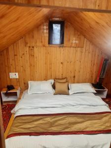 a large bed in a room with a wooden wall at cedar tree cottage gadakufri in Matiāna
