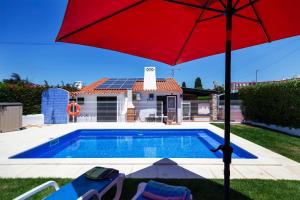 a red umbrella sitting next to a swimming pool at LOTUS VILLA, Albufeira in Albufeira