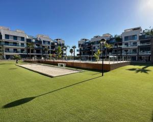 a large grassy field in front of some apartment buildings at Oasis Beach 13 Casa del Guardamar in Alicante