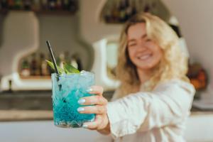 a woman holding a blue drink with a straw at Naxos Cave Suites in Stelida