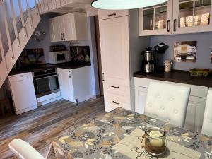 een keuken met witte kasten en een tafel met stoelen bij Hameaux de la plage in Gruissan +2 foto's