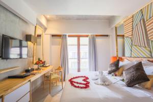 a bedroom with a bed with a desk and a red flower on it at Serela Legian by KAGUM Hotels in Legian