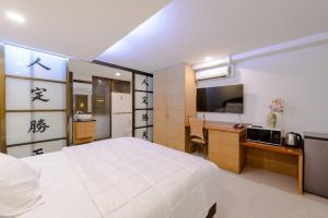 a bedroom with a bed and a desk and a television at Pasadena Lodge in Pattaya Central
