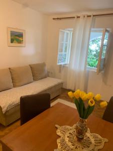 a living room with a couch and a table with yellow flowers at House Orange Apartments in Herceg-Novi