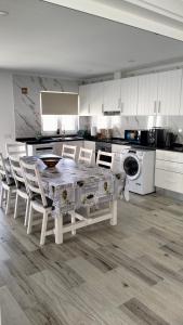 a white kitchen with a table and chairs in it at Paradise Breeze in Carvalhal +8 photos