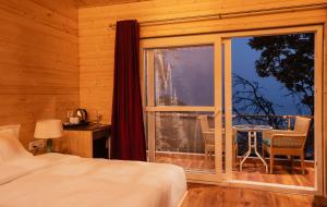 a bedroom with a bed and a window with a table at Sansa by the woods- Manor & Spa in Mussoorie