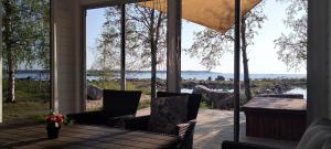 a porch with two chairs and a table with a view of the water at Nelikko juhla- ja majoitustilat in Himanka