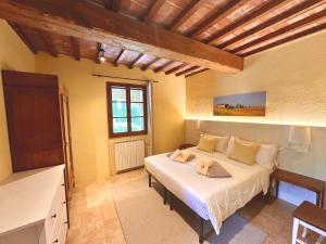 Relais Poggio Del Melograno في بمونتيكاتيني فال دي سيسينا: غرفة نوم بسرير كبير في غرفة