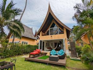 a house with a gambrel roof with a patio at Beachfront Magic Villa - by KohChangVillas in Ko Chang
