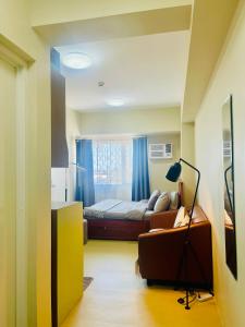 a bedroom with a bed and a couch and a window at City Charm FASTWifi, Netflix, Queen Bed in Cagayan de Oro