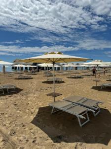 einen Strand mit Liegestühlen und Sonnenschirmen auf dem Sand in der Unterkunft AppArt 24 city center parking and Sea in Lignano Sabbiadoro