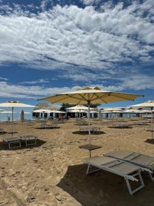una spiaggia con sedie e ombrelloni sulla sabbia di AppArt 21 a Lignano Sabbiadoro