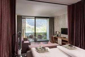 a hotel room with two beds and a large window at Senses Violett Suites - Adults Only in Zell am See