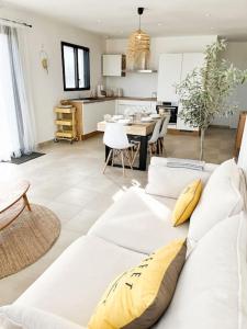 a living room with a white couch and a kitchen at Villa Molène jacuzzi et plage à 500 m in Tréveneuc