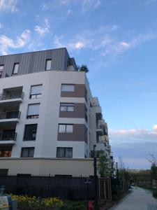 a tall white building with a fence next to a street at Studio indépendant avec terrasse in Villejuif