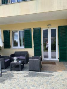 un patio con sillas, mesa y persianas verdes en Villa Oliveto apartments, en Oliveto Lario