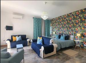 uma sala de estar com sofás azuis e uma parede colorida em Villa Rosa - Sperlonga Vertice Rooms em Sperlonga