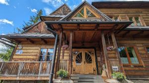 Cabaña de madera con puerta de madera y porche en Willa Orla, en Zakopane