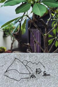 um desenho no lado de uma rocha ao lado de uma planta em Koppie Inn em Xiaoliuqiu