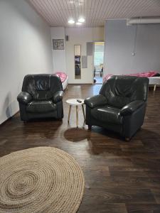 twee zwarte lederen stoelen en een tapijt in een kamer bij Hostelli Karvia in Karvia