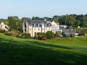 a large house on a golf course with a green yard at Mercure Bayeux Omaha Beach in Port-en-Bessin-Huppain
