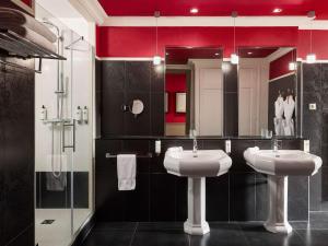 a bathroom with two sinks and a mirror at Le Grand Hotel de Cabourg - MGallery Collection in Cabourg
