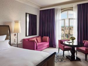 a hotel room with a bed and two pink chairs at Le Grand Hotel de Cabourg - MGallery Collection in Cabourg