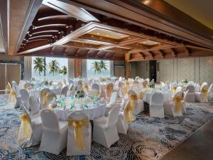 Pullman Pattaya Hotel G في شمال باتايا: قاعة احتفالات بطاولات بيضاء وكراسي بعرصي صفراء