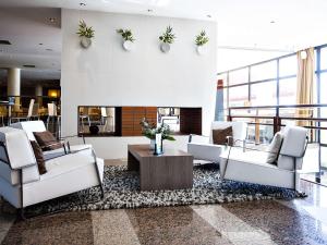 a lobby with white furniture and a fireplace at Mercure Toulouse Aéroport Golf de Seilh in Seilh