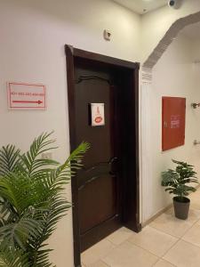 a brown door in a room with two plants at Al Fanar Al Alamaya 3- Hay'aa Malakeya entrance in Yanbu