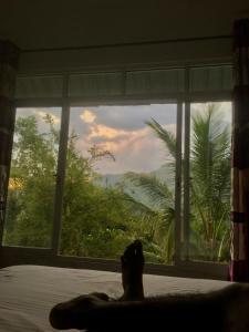 a person laying on a bed looking out a window at Misty View Inn in Ella +21 photos