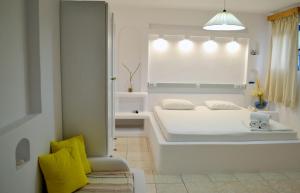 a white bedroom with a large white bed and yellow pillows at Paleochori Studios in Paliochori