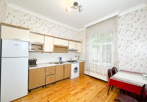 an empty kitchen with a white refrigerator and a table at Love Garden House in Gabala
