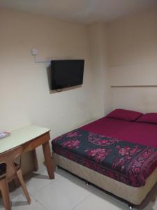 a bedroom with a bed and a table and a tv at KL CITY LODGE in Kuala Lumpur