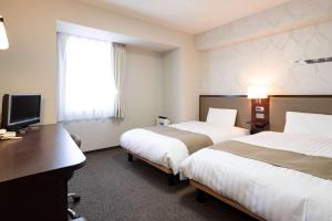 富山市にあるコンフォートホテル富山駅前のベッド2台とデスクが備わるホテルルームです。
