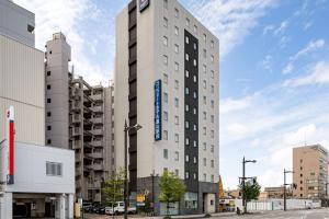 un edificio blanco alto con un letrero azul. en Comfort Hotel Toyama en Toyama