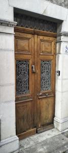 een houten deur op een gebouw met twee ramen bij L'ancien Hôtel du vieux Cèdre in Arreau