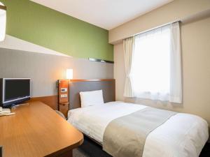 富山市にあるコンフォートホテル富山駅前のベッド、デスク、テレビが備わるホテルルームです。