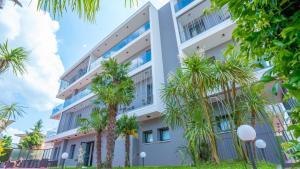 an apartment building with palm trees in front of it at Hotel Bella Peschiera in Peschiera del Garda