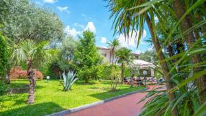 un giardino con palme e un edificio di Hotel Bella Peschiera a Peschiera del Garda