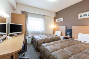 a hotel room with two beds and a desk at Comfort Hotel Kurosaki in Kitakyushu