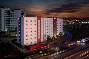 Sleep Inn Tijuana في تيخوانا: مبنى ابيض كبير على شارع المدينة بالليل