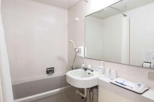 Baño blanco con lavabo y espejo en Comfort Hotel Hamamatsu, en Hamamatsu