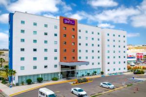 a large white building with a purple sign on it at Sleep Inn Tijuana in Tijuana